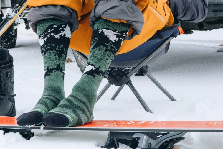 Shop Lightweight Socks - feet wearing green and black ski and snowboard socks with mountain pattern